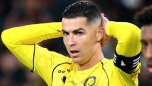 Cristiano Ronaldo in a yellow Al-Nassr kit, with his hands on his head, displaying a tense moment during a match.