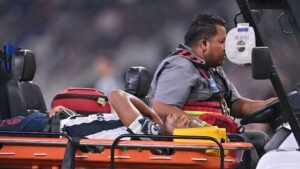 Anthony Martial being taken on a stretcher by medical staff following an injury during a match, with a medical cart in the foreground.