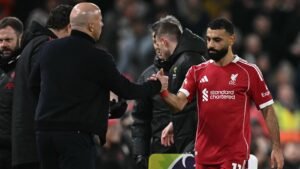 Arne Slot schudt Mohamed Salah de hand op het veld van Anfield, wat hun hernieuwde kameraadschap na het conflict benadrukt.