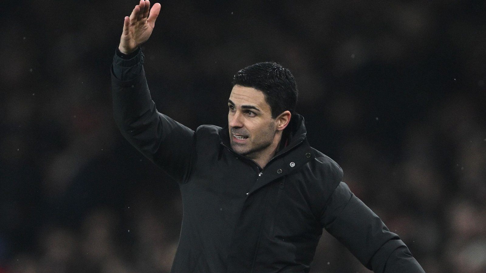 Mikel Arteta gesticue pendant un match, portant un manteau noir, mettant en lumière sa direction stratégique pour Arsenal avant le derby du nord de Londres.