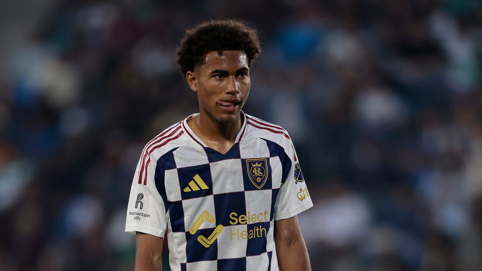 Le milieu de terrain du Real Salt Lake portant le maillot rayé bleu marine et blanc de l'équipe, affichant une expression concentrée pendant un match.