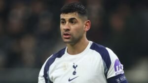 Le capitaine de Tottenham, Cristian Romero, apparaît concentré lors d'un match, portant un maillot blanc et marine sali, avec le logo des Spurs bien visible.