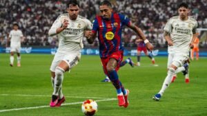 Barcelona's player in a red and blue kit sprinting with the ball, chased by two Real Madrid players in white jerseys during El Clásico.