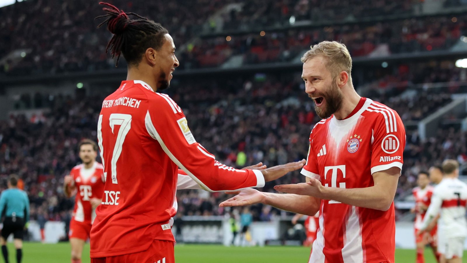 Bayern Munich players celebrate a goal, with Michael Olise (17) and a teammate expressing joy on the pitch during a match.