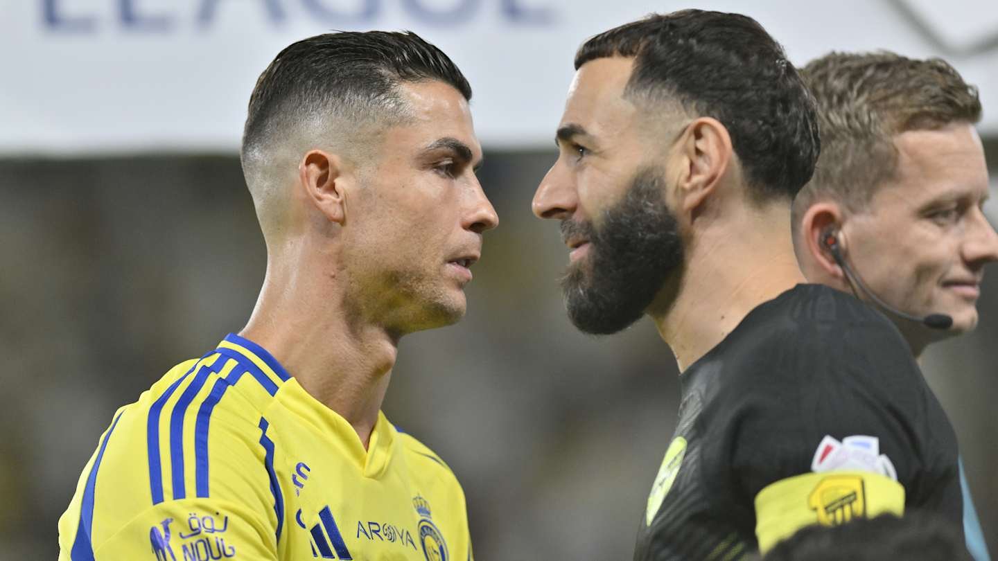 Cristiano Ronaldo and Karim Benzema face each other during a tense moment in a match, wearing their club colours.