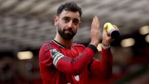 Bruno Fernandes, vêtu du maillot rouge de Manchester United avec le brassard de capitaine, salue les supporters, célébrant ses 200 contributions pour le club.