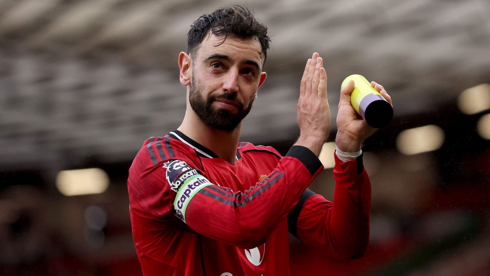 Bruno Fernandes, vêtu du maillot rouge de Manchester United avec le brassard de capitaine, salue les supporters, célébrant ses 200 contributions pour le club.