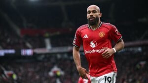 Bryan Mbeumo in Manchester United's red kit, sprinting at Old Trafford during a match with Adama Traore in pursuit.