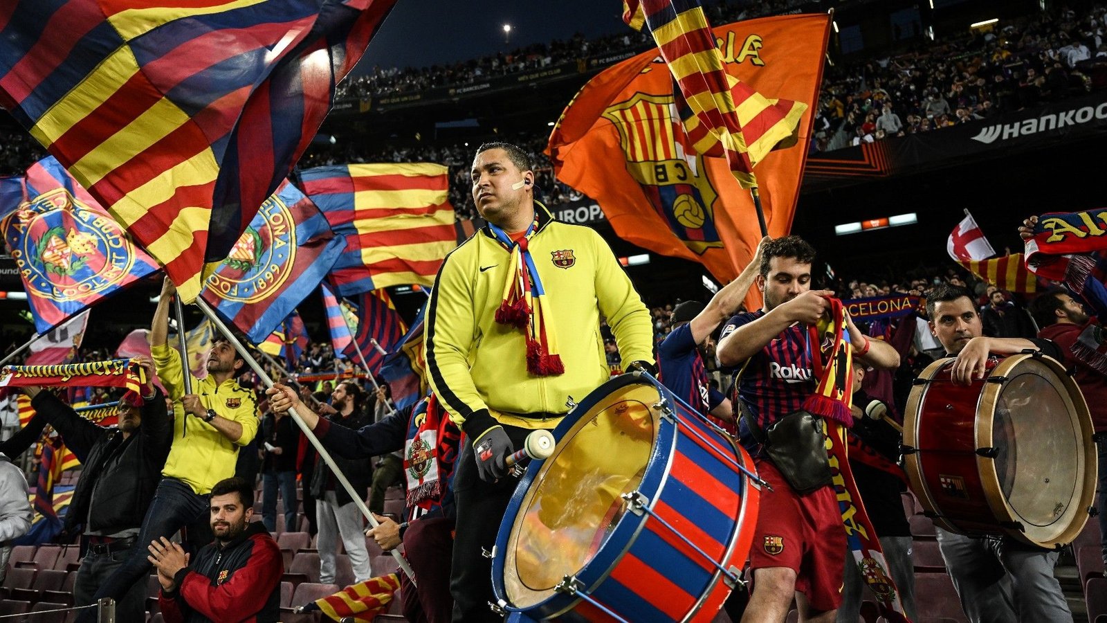 Barcelona-fans vieren gepassioneerd met vlaggen en trommels tijdens een wedstrijd in Camp Nou, waarbij ze hun teamgeest en levendige kleuren tonen.