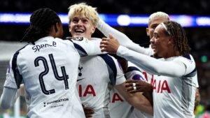 Spurs-spelers vieren een doelpunt, met vrolijke uitdrukkingen, witte en marineblauwe tenues, waarbij rugnummer 24 zichtbaar is.