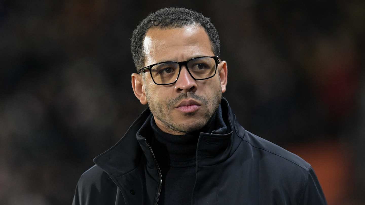 Moroccan football manager in a dark jacket and glasses, reflecting on a match, showcases the intensity of coaching.