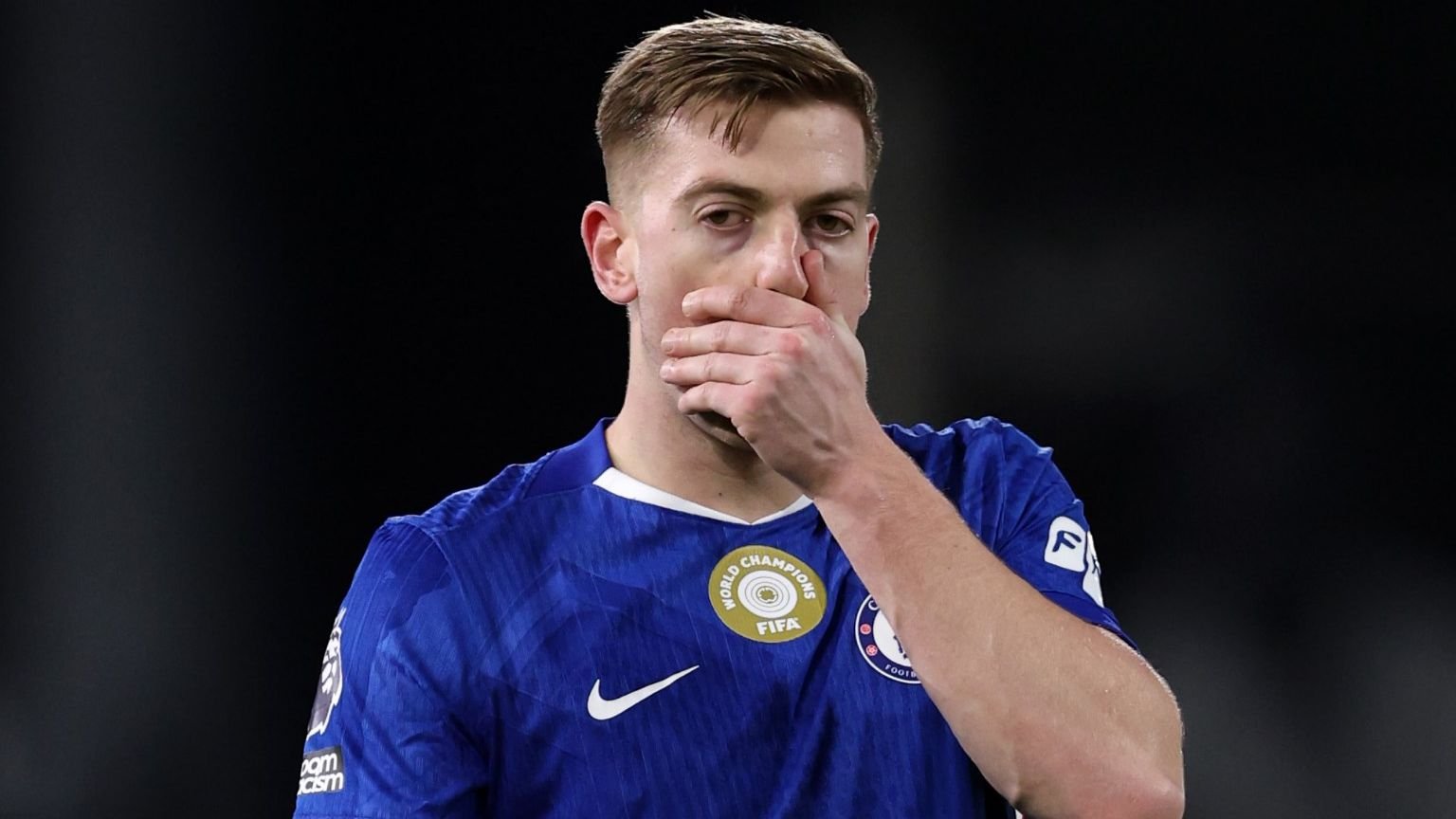 Liam Delap in Chelsea's blue kit looks dejected after a missed opportunity against Hull, highlighting a moment of disappointment.