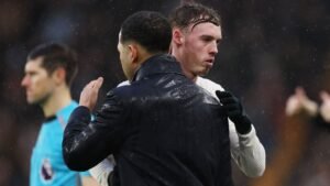 Cole Palmer étreint son entraîneur, vêtements trempés par la pluie, après un match intense, mettant en lumière l’esprit d’équipe dans des conditions difficiles.