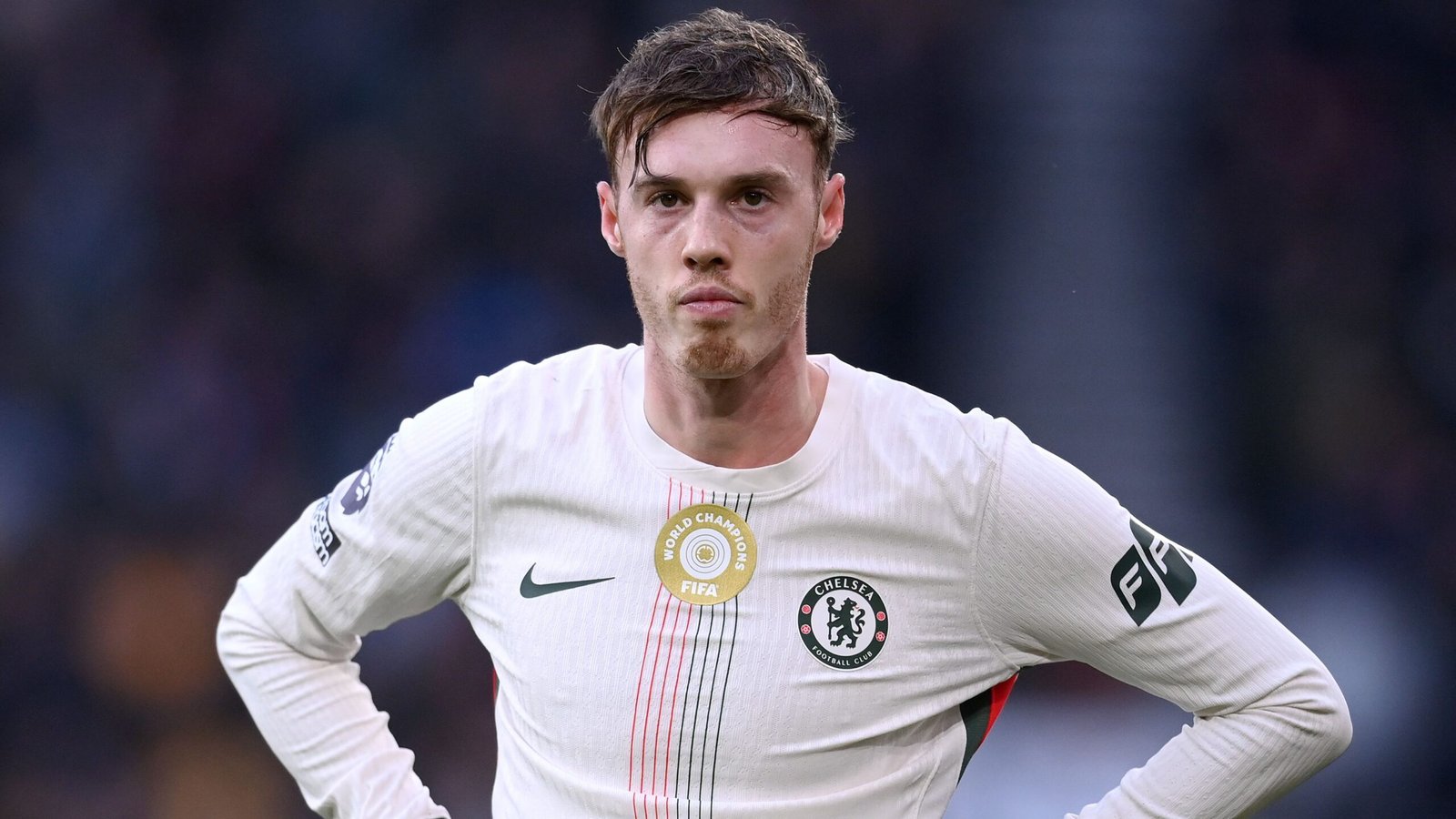 Cole Palmer, abattu, porte le maillot de Chelsea lors d'un match, arborant le blason du club et le patch FIFA sur son équipement.