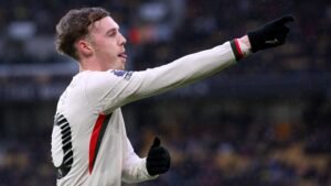 Cole Palmer viert zijn doelpunt voor Chelsea tegen Wolves, gekleed in het witte tenue van het team, met een duim omhoog en een uitgestoken wijzende vinger.