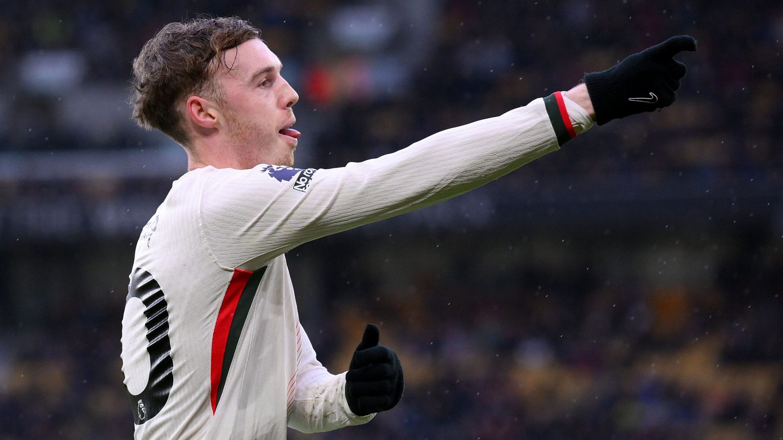 Cole Palmer viert zijn doelpunt voor Chelsea tegen Wolves, gekleed in het witte tenue van het team, met een duim omhoog en een uitgestoken wijzende vinger.