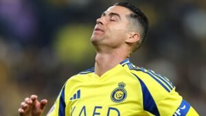 Cristiano Ronaldo dans un maillot jaune d'Al Nassr, affichant une expression frustrée pendant un match, avec une foule floue en arrière-plan.