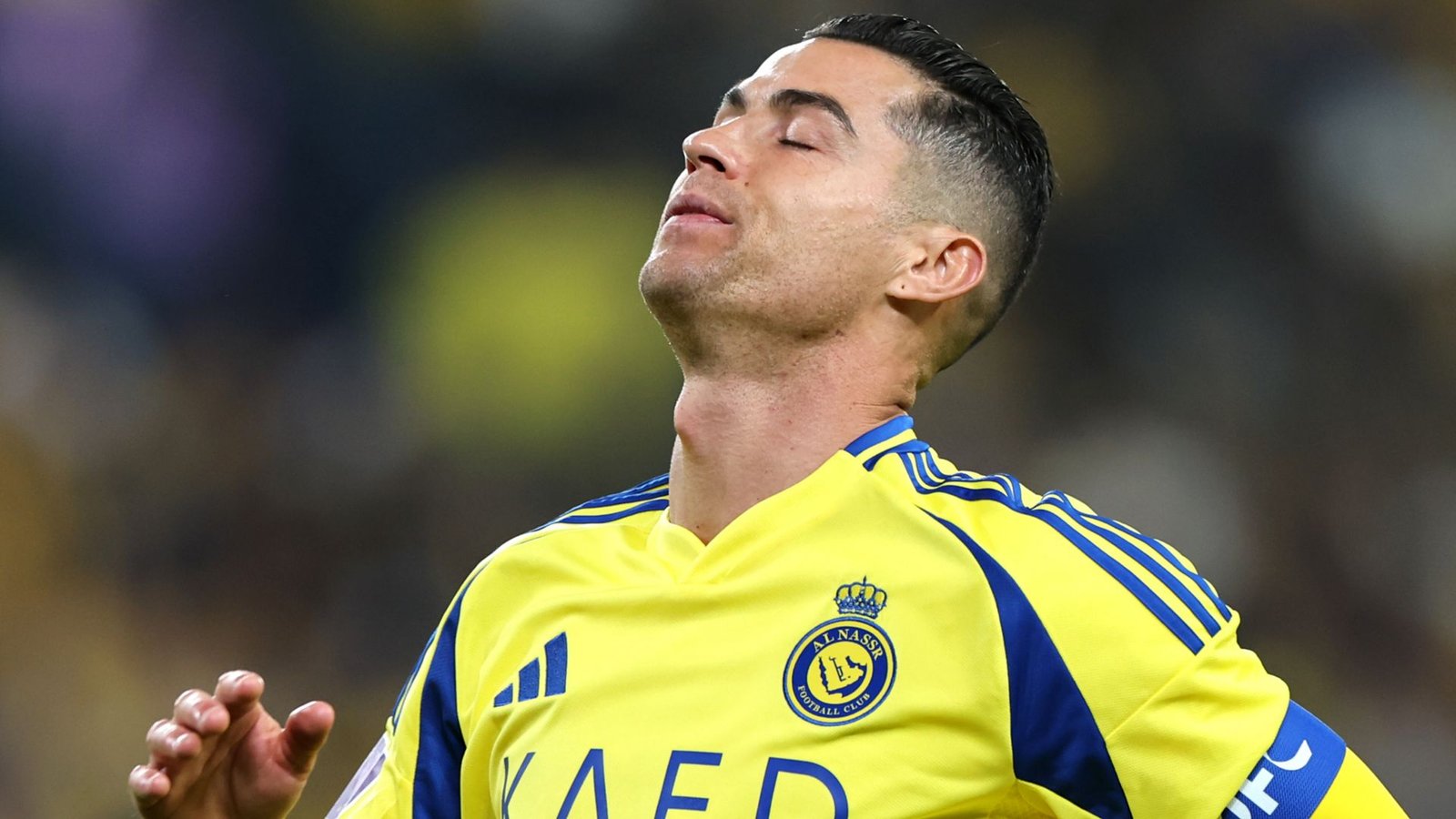 Cristiano Ronaldo dans un maillot jaune d'Al Nassr, affichant une expression frustrée pendant un match, avec une foule floue en arrière-plan.