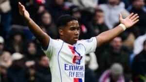 Endrick, vêtu du maillot blanc de l'Olympique Lyonnais aux accents rouges et bleus, gesticule en direction de l'arbitre après avoir reçu un carton rouge lors d'un match.