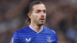 Everton-speler in blauw thuistenue tijdens een wedstrijd, met een geconcentreerde uitdrukking tegen een wazige stadionachtergrond.