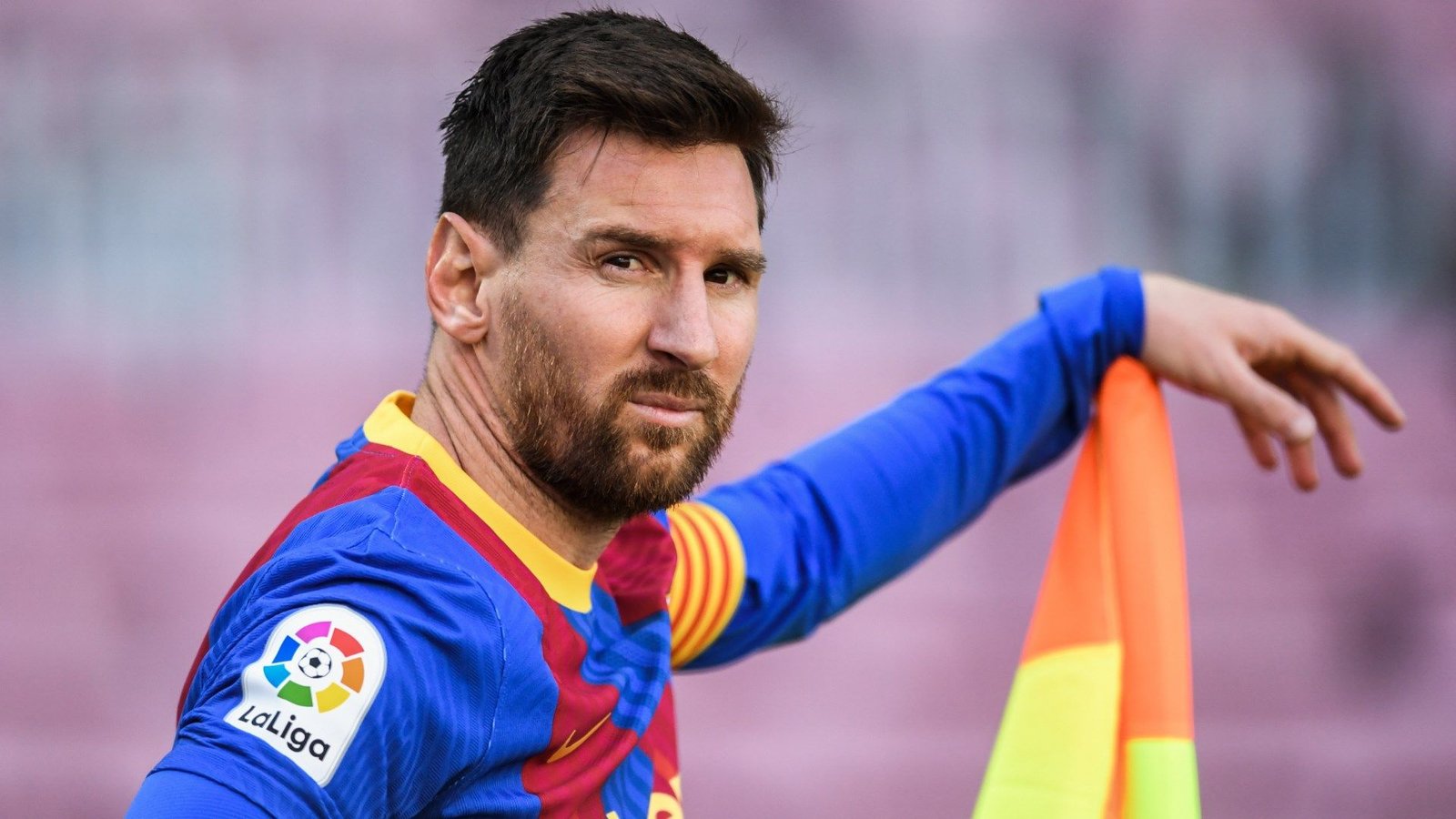 Lionel Messi, vêtu du maillot bleu et grenat du Barça, fixe pensivement un drapeau lors d'un match de Liga.