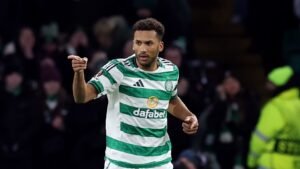 Celtic-verdediger Auston Trusty viert op het veld, gekleed in het groen-wit gestreepte tenue van het team, terwijl op de achtergrond juichende fans te zien zijn.