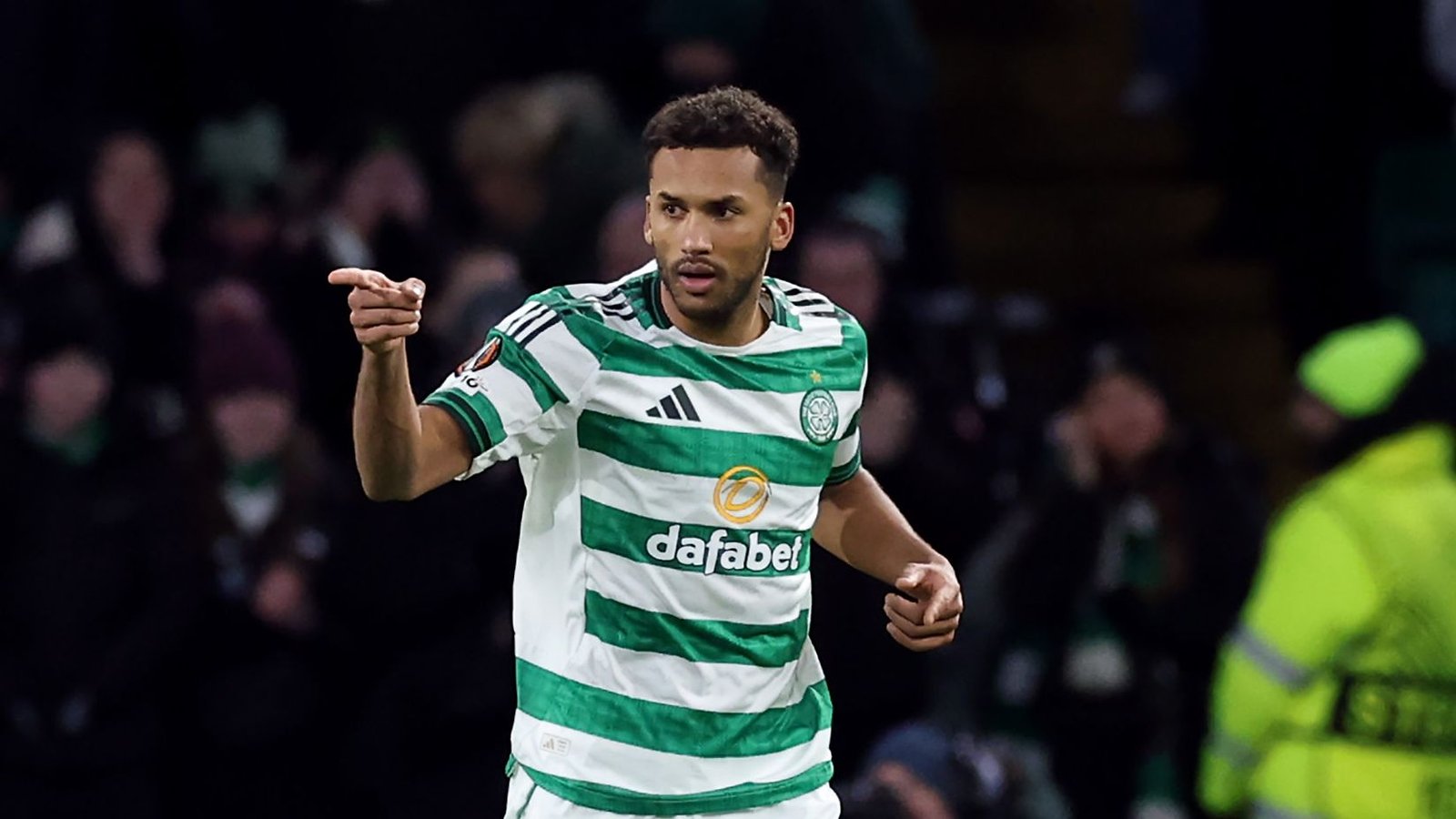 Celtic-verdediger Auston Trusty viert op het veld, gekleed in het groen-wit gestreepte tenue van het team, terwijl op de achtergrond juichende fans te zien zijn.