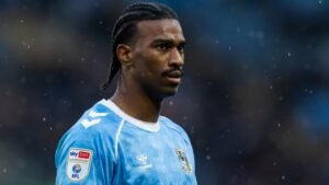 Haji Wright in Coventry City's light blue kit, focused during a match, showcasing his determination on the pitch.