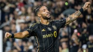 Un joueur du LAFC célèbre un but, portant un maillot noir et or avec le logo 'BMO', entouré de supporters enthousiastes dans le stade.