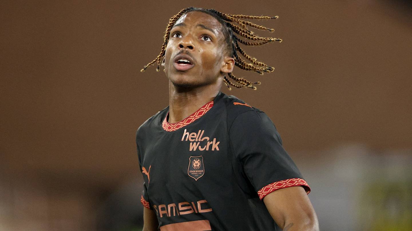 Jeremy Jacquet en tenue noire de Rennes, regardant vers le haut pendant un match, arborant sa coiffure tressée distinctive.