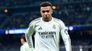 Kylian Mbappé portant le maillot blanc du Real Madrid, concentré lors d'un match au stade Santiago Bernabéu, démontrant sa détermination.