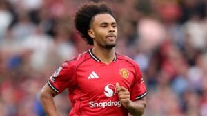 Joshua Zirkzee portant le maillot domicile rouge de Manchester United, concentré pendant un match, faisant preuve de détermination et d'esprit d'équipe.