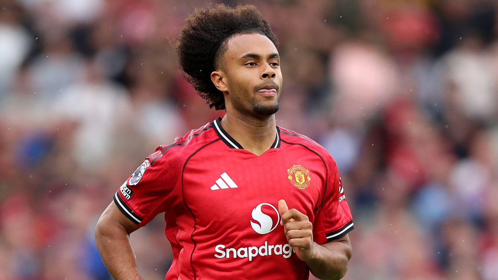 Joshua Zirkzee portant le maillot domicile rouge de Manchester United, concentré pendant un match, faisant preuve de détermination et d'esprit d'équipe.