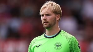 Le gardien de Brentford, Kelleher, vêtu d'un maillot vert vif, concentré sur le match, fait preuve de détermination sur le terrain.