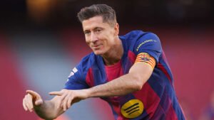 Robert Lewandowski, wearing Barcelona's maroon and blue kit, gestures with a smile, showcasing his captain's armband at Camp Nou.