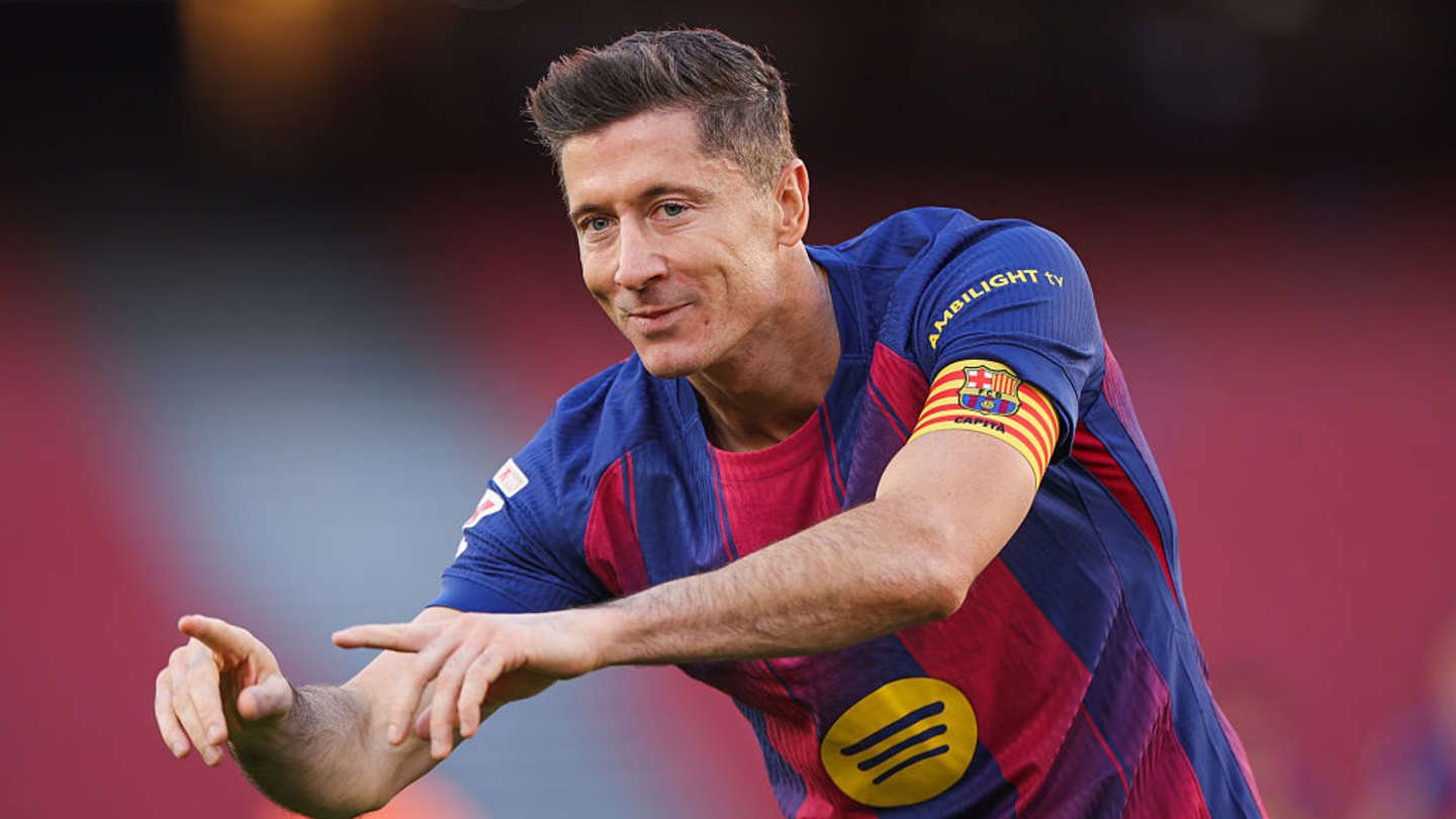Robert Lewandowski, wearing Barcelona's maroon and blue kit, gestures with a smile, showcasing his captain's armband at Camp Nou.