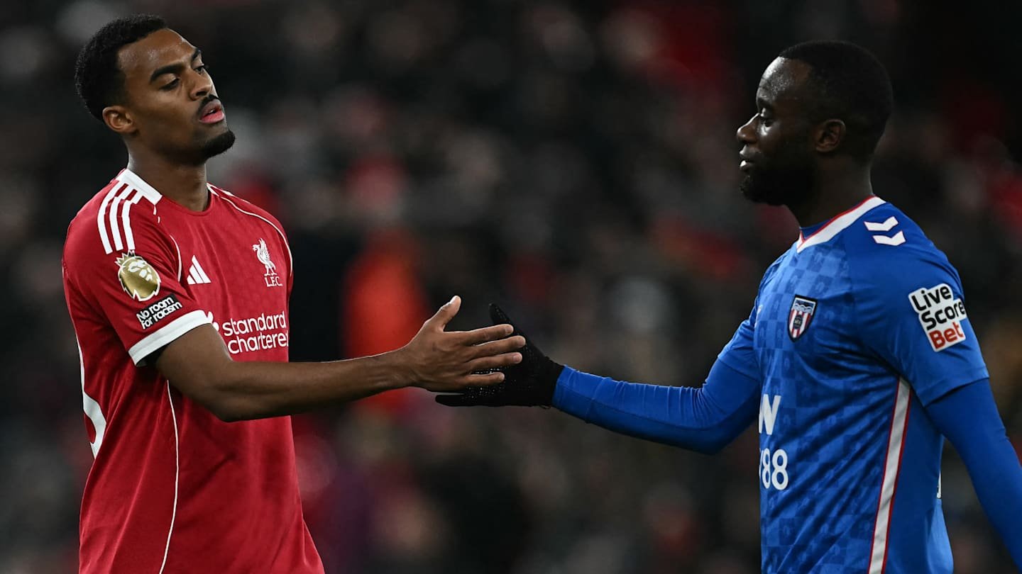 Les joueurs de Liverpool se saluent sur le terrain, portant leur célèbre tenue rouge et une tenue bleue de gardien lors d'un match tendu de Premier League.