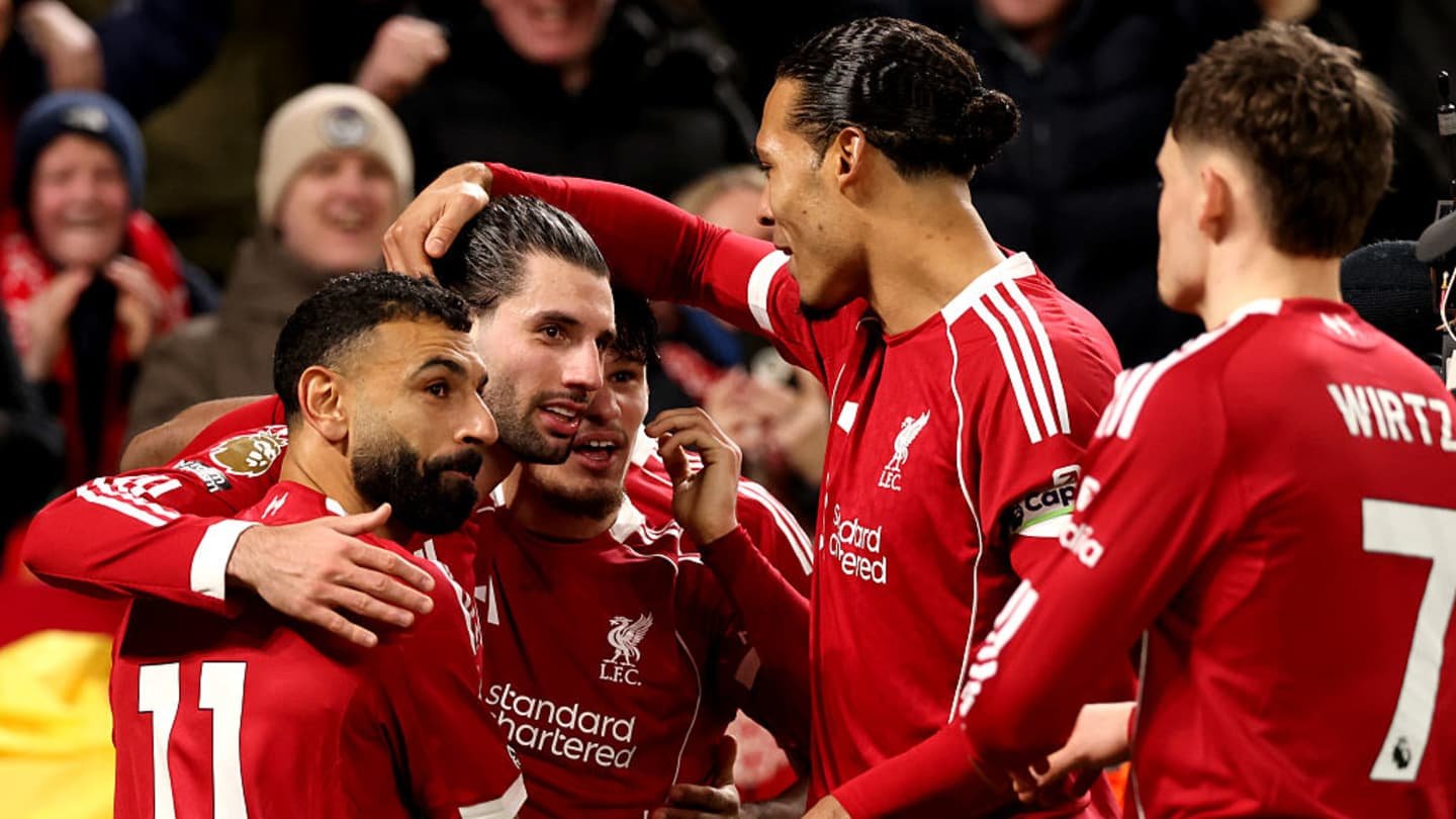 Liverpool players celebrate a goal, featuring Mohamed Salah, Virgil van Dijk, and Emre Can, in vibrant red kits amid cheering fans.