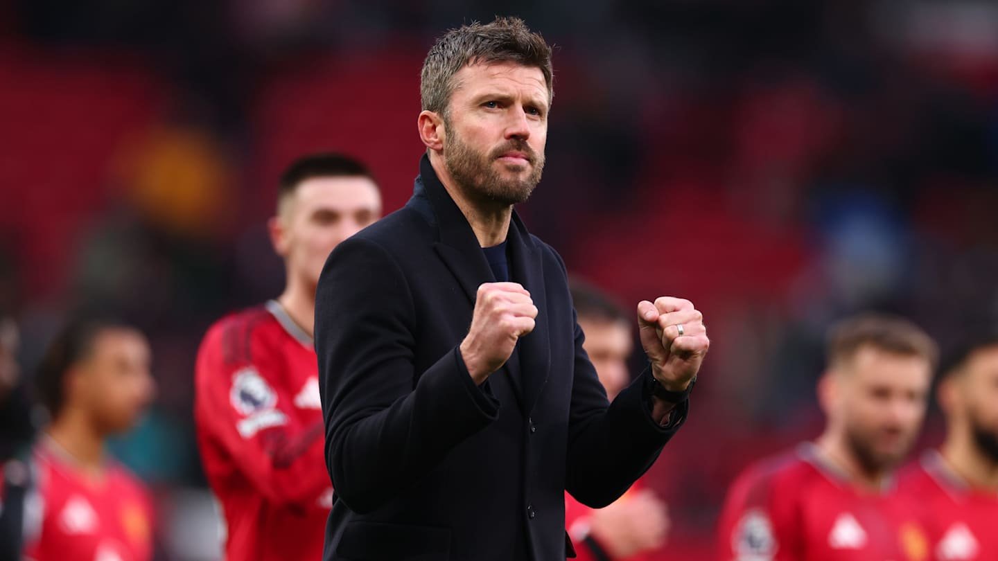 Michael Carrick celebrates after a match at Old Trafford, wearing a black coat and showing excitement with clenched fists.