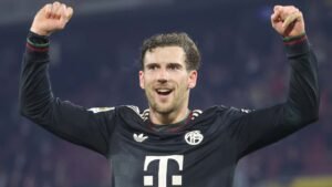 Leon Goretzka celebrates in Bayern Munich's black kit, raising his arms in triumph after a notable match victory.