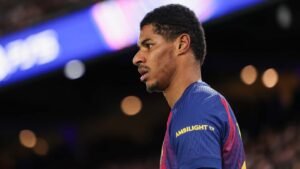 Marcus Rashford in Manchester United's home kit, with a focused expression during a match, showcasing the club's iconic red colours.