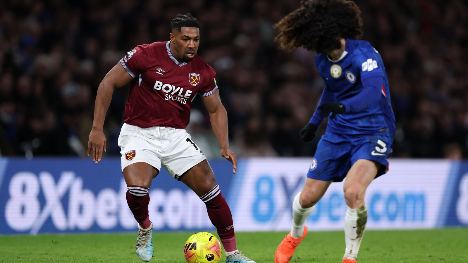 Adama Traoré dribbles past Marc Cucurella during a Premier League match between West Ham United and Chelsea, showcasing intense action.