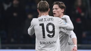 Scott McTominay et Rasmus Højlund célèbrent un but dans les derniers instants, portant tous deux des maillots blancs arborant les noms ' HØJLUND ' et ' SORGESANA ' au dos.
