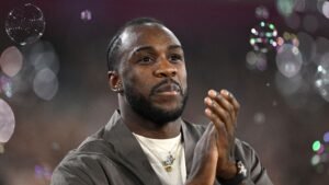 Michail Antonio applaudisseert met bubbels op de achtergrond, wat een feestelijke sfeer toont tijdens een voetbalevenement.