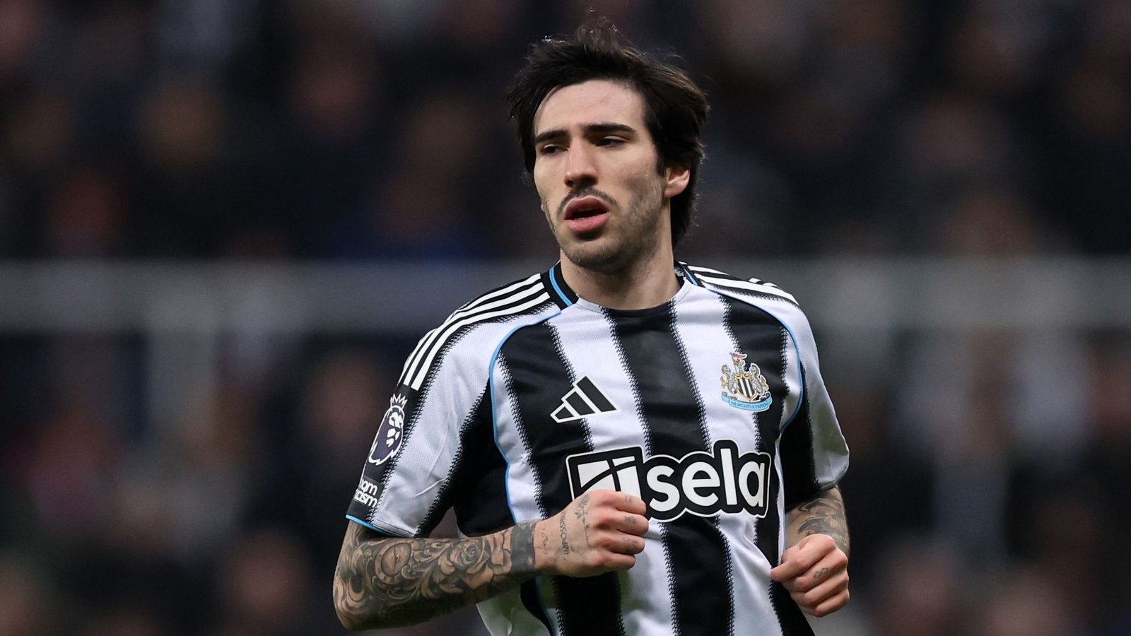 Sandro Tonali, en tenue rayée noir et blanc de Newcastle lors d'un match de Premier League, concentré et en mouvement sur le terrain.