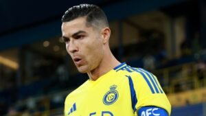 Cristiano Ronaldo portant le maillot jaune et bleu d'Al Nassr, l'air concentré avant un match, mettant en avant son leadership en tant que capitaine.