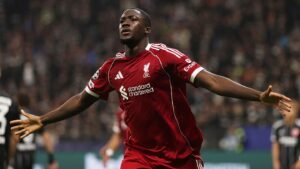 Ibrahima Konaté celebrating a goal for Liverpool, wearing the team's red kit, with an ecstatic expression in a vibrant stadium backdrop.