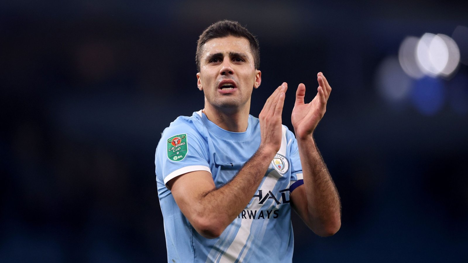 Rodri applaudisseert voor fans in het Etihad Stadium, gekleed in Manchester City's hemelsblauwe tenue tijdens een bekerwedstrijd.