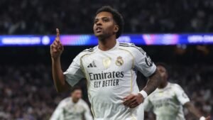 Rodrygo celebrates after scoring, wearing Real Madrid's white kit with the Emirates logo, during a UEFA Champions League match.