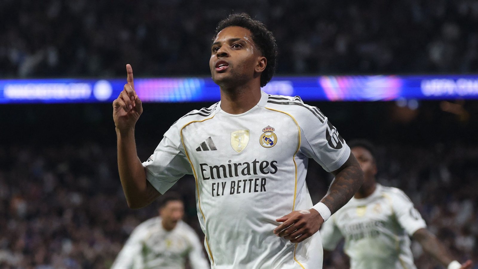 Rodrygo celebrates after scoring, wearing Real Madrid's white kit with the Emirates logo, during a UEFA Champions League match.